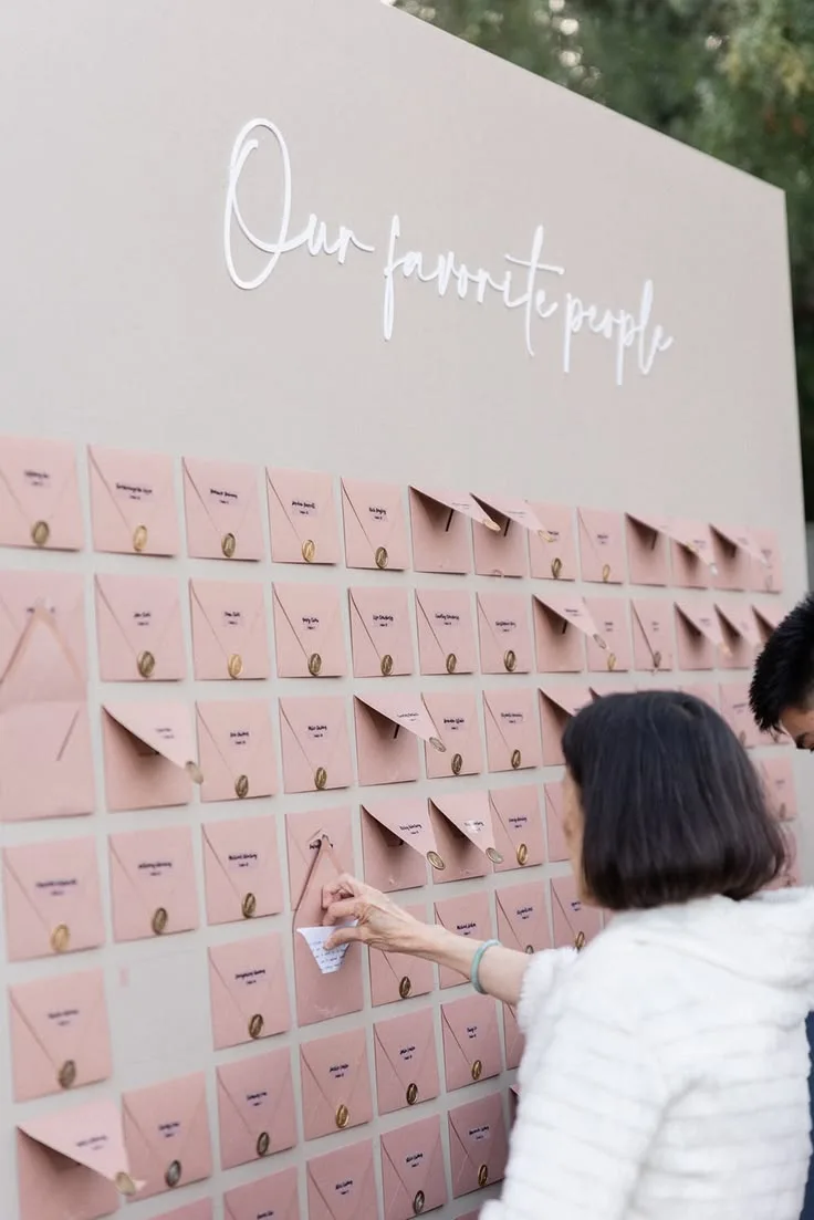 A guest picking their seat card from a wall reading Our favorite people