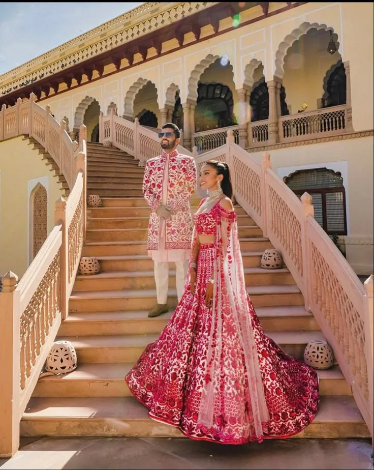 A couple in coordinated wedding outfits on a palace staircase